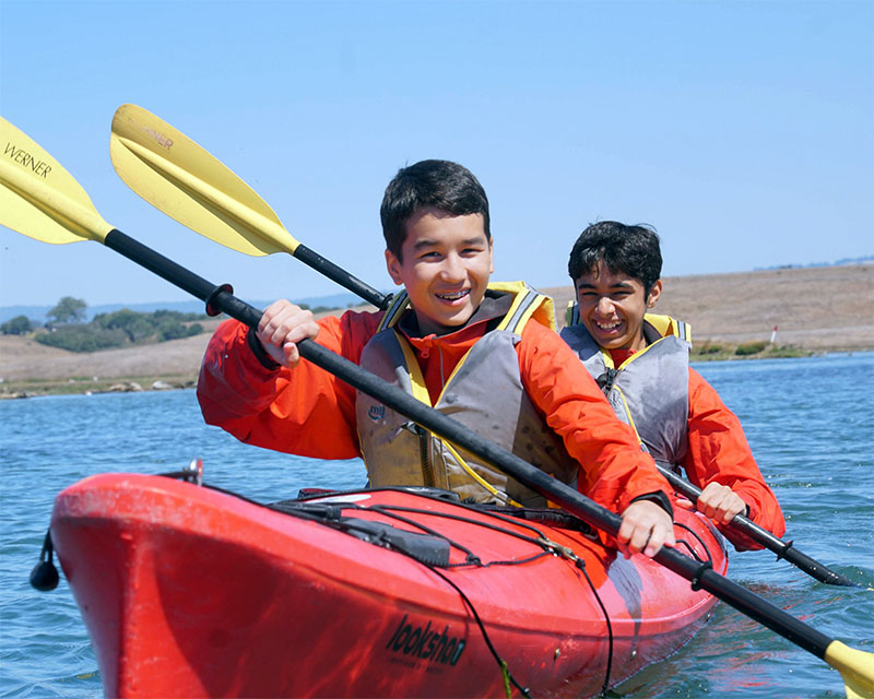 two male students paddling a kayak