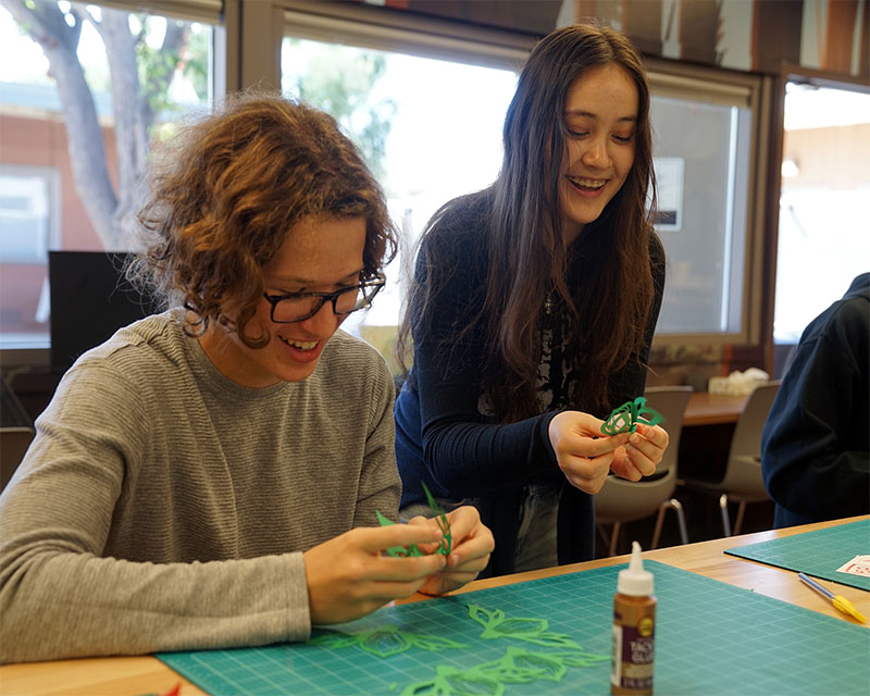 two female students smile as they work together on a project