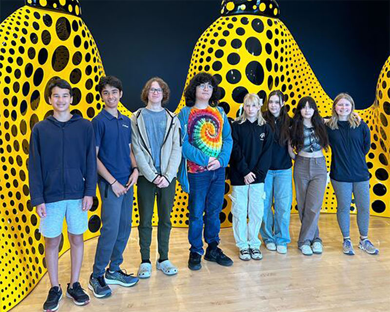 students stand in front of a curvy yellow sculpture at SFMOMA